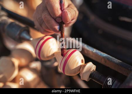 Handgefertigte Produktionsstufe des Spinning Top. Ein Holzschnitzer malte die Drehplatte auf der alten Drehmaschine. Stockfoto