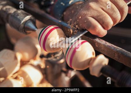 Handgefertigte Produktionsstufe des Spinning Top. Ein Holzschnitzer, der das Holz auf der alten Drehbank schnitzt. Stockfoto