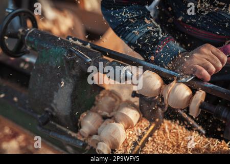 Handgefertigte Produktionsstufe des Spinning Top. Ein Holzschnitzer, der das Holz auf der alten Drehbank schnitzt. Stockfoto