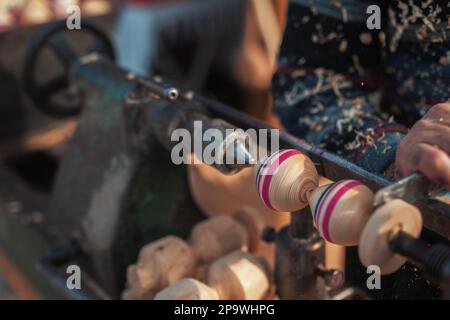 Handgefertigte Produktionsstufe des Spinning Top. Ein Holzschnitzer, der das Holz auf der alten Drehbank schnitzt. Stockfoto