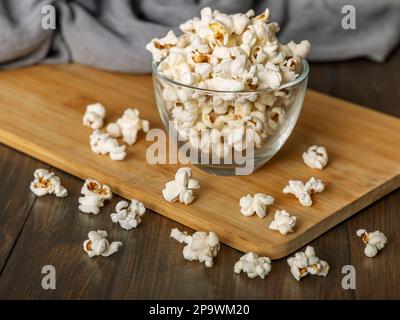 Popcorn in Glasschüssel auf Holzhintergrund Stockfoto