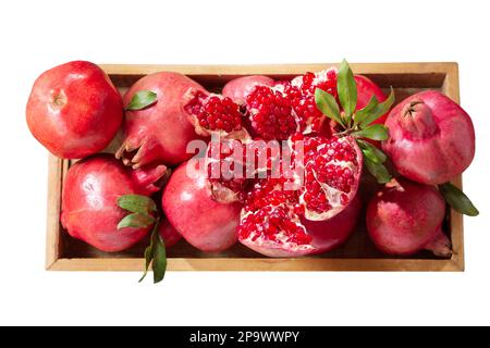 Frische reife Granatäpfel in einem Holzkasten isoliert auf weißem Hintergrund, Draufsicht Stockfoto