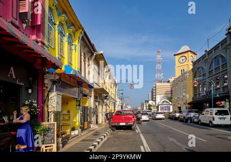 Farbenfrohe Geschäfte im chinesisch-portugiesischen Stil in der Phang-Nga Rd In der Altstadt von Phuket Town, Thailand, mit dem berühmten Phromthep Clocktower in b/g Stockfoto