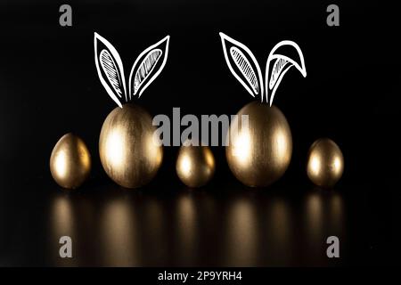 Frohe Ostern, Kaninchenohren, goldene Eier. Stockfoto