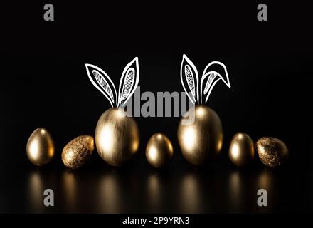 Frohe Ostern, Kaninchenohren, goldene Eier. Stockfoto