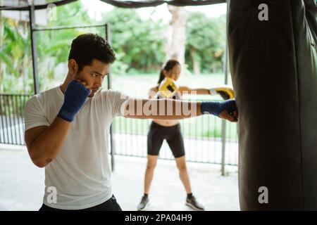 Der Boxer und die Boxerin, die auf den Sandsack schlagen Stockfoto