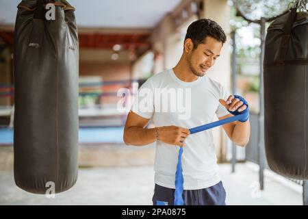 Ein asiatischer Boxer, der Boxhandschuhe trägt, während er im Ring steht Stockfoto