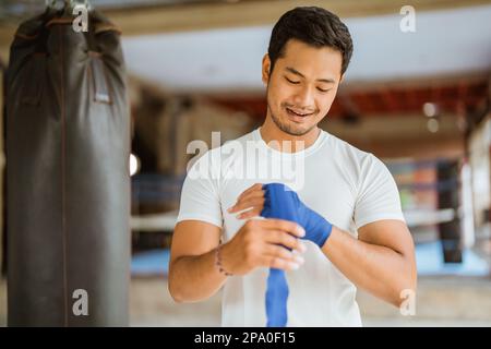 Ein asiatischer Boxer, der Boxhandschuhe trägt, während er im Ring steht Stockfoto