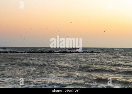 Nahaufnahme des eisigen Meeres, gefrorene Wellen, Felsen und Sonnenblendung auf dem Eis. Stockfoto