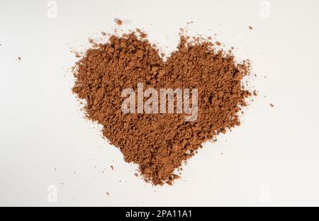 Herzförmiges Kakaopulver, gehärtet auf weißem Hintergrund. Stockfoto