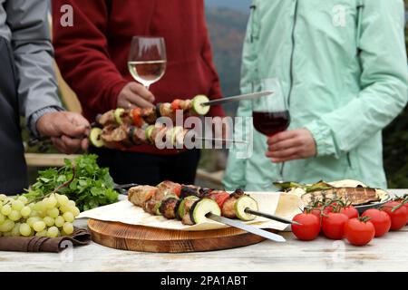 Freunde, die im Freien eine Barbecue-Party feiern, konzentrieren sich auf köstliche Speisen am Tisch Stockfoto