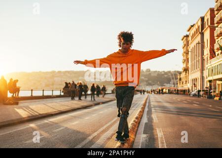 Junger afrikaner, der Spaß hat, bei Sonnenuntergang an der Stadt vorbeizulaufen - weicher Fokus auf das Gesicht Stockfoto