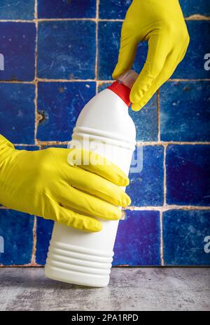 Waschmittelflasche in den Händen in Handschuhen, öffnendes WC und Reinigungsgel im Badezimmer, flüssig. Stockfoto