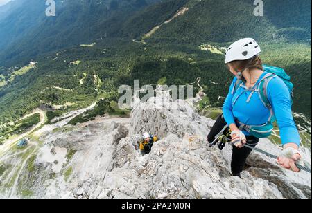 Zwei junge, attraktive Bergsteiger auf der sehr exponierten Via Ferrata in Alta Badia in den italienischen Dolomiten Stockfoto