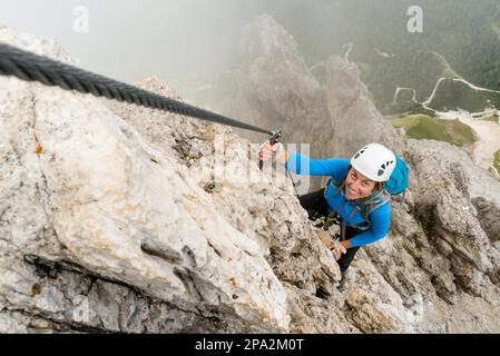 Junge attraktive Bergsteigerin auf einer steilen und exponierten Via Ferrata in Alta Badia in Südtirol in den italienischen Dolomiten Stockfoto