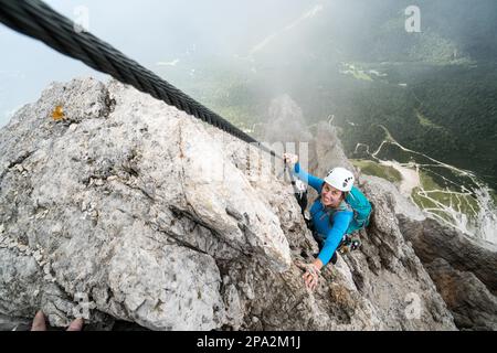 Junge attraktive Bergsteigerin auf einer steilen und exponierten Via Ferrata in Alta Badia in Südtirol in den italienischen Dolomiten Stockfoto