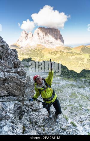 Junge attraktive Bergsteigerin in den Dolomiten Italiens mit einem großartigen Blick auf Langkofel und Passo Sella Stockfoto