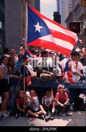 Begeisterte Zuschauer auf der Straße, um bei der jährlichen Puerto Rican Day Parade auf der 5. Avenue in New York City die Marscher anzufeuern. Stockfoto