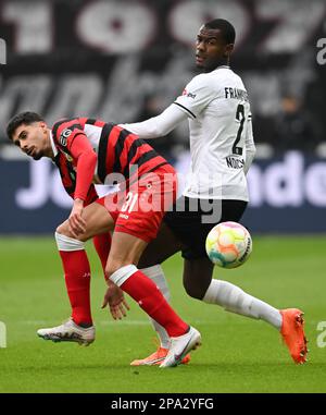 11. März 2023, Hessen, Frankfurt/Main: Fußball: Bundesliga, Eintracht Frankfurt - VfB Stuttgart, Spieltag 24 im Deutsche Bank Park. Evan Ndicka (r) in Frankfurt und Gil Bastiao Dias in Stuttgart kämpfen um den Ball. Foto: Arne Dedert/dpa - WICHTIGER HINWEIS: Gemäß den Anforderungen der DFL Deutsche Fußball Liga und des DFB Deutscher Fußball-Bund ist es verboten, im Stadion aufgenommene Fotografien und/oder das Spiel in Form von Sequenzbildern und/oder videoähnlichen Fotoserien zu verwenden oder verwenden zu lassen. Stockfoto