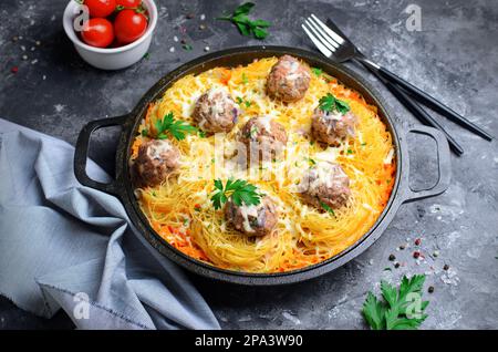Nudelgerichte mit Fleischbällchen und Tomatensoße auf einem Teller, frisch zubereitete Pasta, leckeres Essen, dunkler Hintergrund Stockfoto