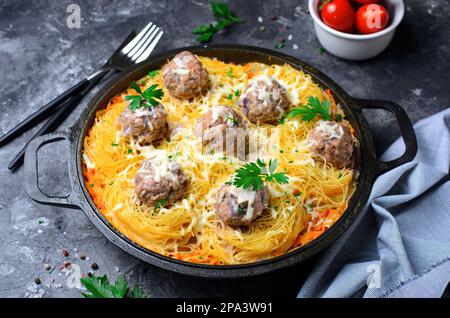 Nudelgerichte mit Fleischbällchen und Tomatensoße auf einem Teller, frisch zubereitete Pasta, leckeres Essen, dunkler Hintergrund Stockfoto