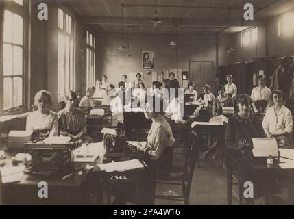 Foto einer großen Gruppe von weiblichen Büroangestellten oder Sekretärinnen aus der Zeit des Ersten Weltkriegs. Die meisten Frauen sitzen vor Schreibmaschinen, mit Bögen Papier um sie herum. Ein Poster auf der Rückseite des Raumes enthält ein Bild von Feldmarschall Douglas Haig mit der Überschrift „jeder Arbeitgeber kann helfen, wenn Sie einen ehemaligen Servicemitarbeiter einstellen und ausbilden, der für Handel oder die Berufe geeignet ist“ Stockfoto