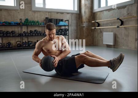 Ein Mann, der Fitnesstraining macht, bauchmuskeltraining mit Medizinball im Fitnessstudio macht Stockfoto