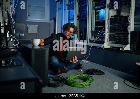 IT-Techniker, der während der Arbeit im Rechenzentrum ein Notebook verwendet Stockfoto