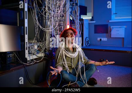 Gestresster Computeringenieur, der versucht, das Chaos im Netzwerk zu verstehen Stockfoto