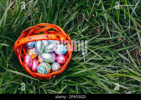 Schokoladen-Ostereier im Korb auf grünem Gras im Hintergrund schön Stockfoto