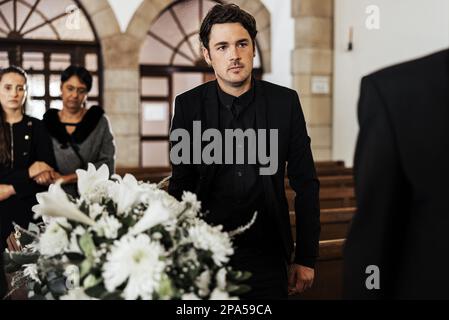 Beerdigung, Tod und Trauer mit einem Mann, der während einer Zeremonie einen Sarg in einer Kirche trug. Blumen, Anzug und Verlust mit einem Männchen, das eine Schatulle hält Stockfoto