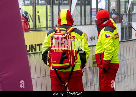 Ostrava, Tschechien - 02.04.2023: Zwei männliche Sicherheitsärzte in leuchtend grünen reflektierenden Westen mit Blick auf den Rennrennen-Wettkampf in der Stadt. Unschuldiger Winter r Stockfoto