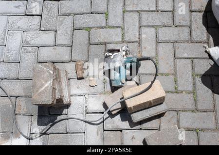 Kleine Betonsäge neben Steinblöcken mit sonniger Sicht von oben. Stockfoto