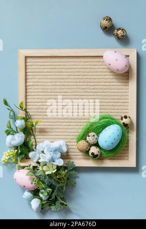 Brieftafel, Ostereier und Frühlingsblumen auf pastellblauem Hintergrund. Frühlingskonzept zur Begrüßung. Blick von oben. Stockfoto