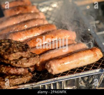 Würstchen und Beefburger auf einem Einweg-BBQ Stockfoto