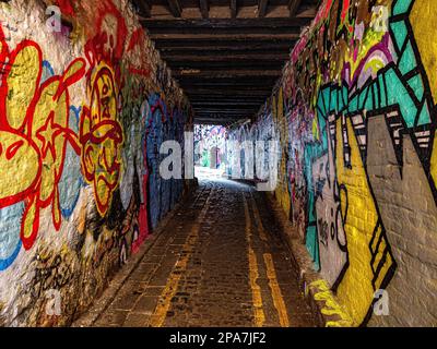 Farbenfrohe, mit Graffiti bedeckte Wände einer engen Gasse in der Nähe der Corn Street in der Altstadt von Bristol UK Stockfoto