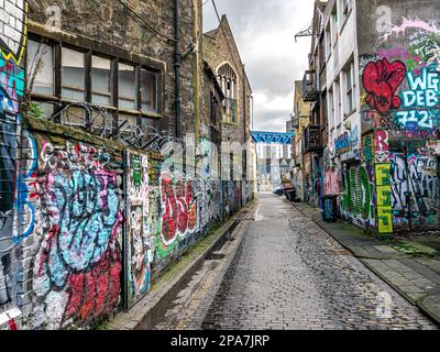 Graffiti covered walls of a narrow alley in the Stokes Croft area close to the city centre of Bristol UK Stock Photo