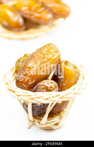 Nahaufnahme der algerischen königlichen Datteln auf einer Holzplatte auf weißem Hintergrund. Ramadan-Konzept. Stockfoto