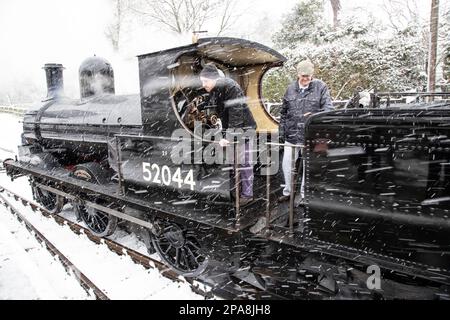 Dampflokomotive 52044 Klasse 25 Ironclad, die im Film "Railway Children" mitspielte, fährt bei einem Schneesturm in die Station Oxenhope Stockfoto