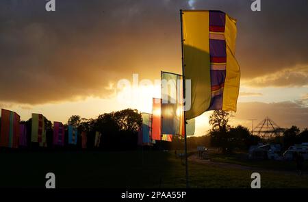 Farbenfrohe Banner auf der Worthy Farm, Pilton, dem Veranstaltungsort des Glastonbury Festivals, am frühen Abend bei Sonnenuntergang. Stockfoto