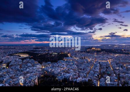 Blick auf die Stadt Athen während eines herrlichen Sonnenuntergangs. Auf der rechten Seite sehen Sie die Akropolis und den Parthenon, und auf der unteren linken Seite das Parlament. Stockfoto