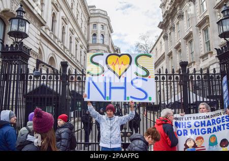 London, Großbritannien. 11. März 2023. Während der Demonstration außerhalb der Downing Street hat ein Demonstrante ein Schild mit dem Titel „SOS NHS“. Tausende von Menschen marschierten durch das Zentrum von London, um den NHS (National Health Service) und NHS-Arbeiter zu unterstützen und gegen die Privatisierung des NHS zu protestieren. Kredit: SOPA Images Limited/Alamy Live News Stockfoto