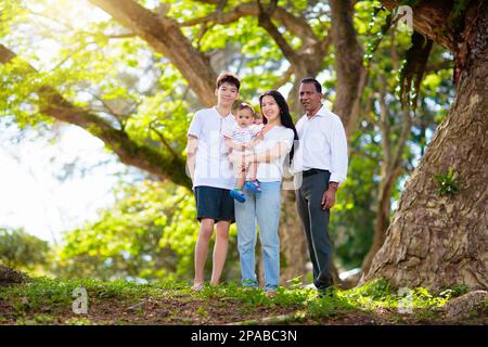 Familienspaziergängen im Sommerpark. Eltern und Kinder im Freien. Mutter, Vater und Kinder spielen, lachen, picknicken im sonnigen Garten. Stockfoto