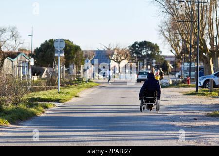 Person im Rollstuhl auf der Straße an einem sonnigen Tag Stockfoto