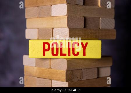 Konzept Wort "Politik" auf Holzwürfel zwischen den Seiten eines Buches auf einem schönen Holztisch. Weißer Hintergrund. Geschäftskonzept. Stockfoto