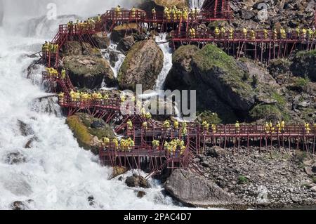 Niagara Falls Town, ON, Kanada - 30. Mai 2015: Gruppe von Touristen in gelben Regenmänteln, die die Niagarafälle beobachten und Fotos machen Stockfoto