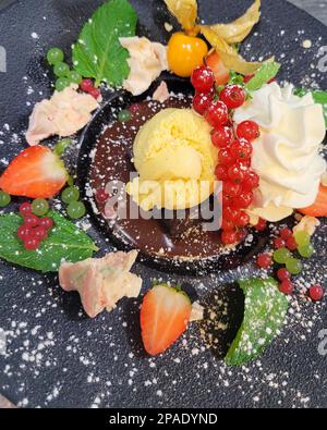 Köstliches Dessert, Schokoladen-Brownie mit Eis und Obst Stockfoto