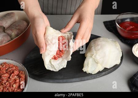 Eine Frau, die gefüllte Kohlrollen am grauen Tisch zubereitet, Nahaufnahme Stockfoto