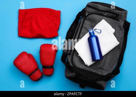 Sporttasche und Sportausrüstung auf hellblauem Hintergrund, flach liegend Stockfoto