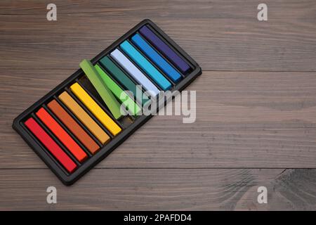 Farbenfrohe Pastelltöne im Tablett auf einem Holztisch, Platz für Text. Zeichenmaterialien Stockfoto